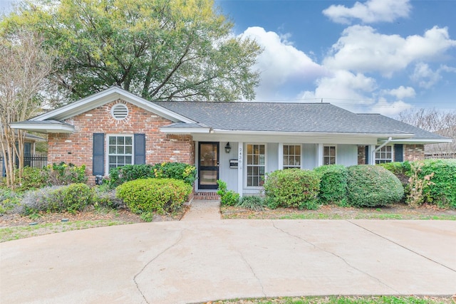 ranch-style home featuring roof with shingles and brick siding