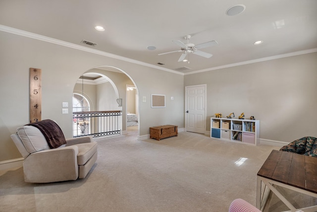 carpeted living room with baseboards, visible vents, arched walkways, and crown molding