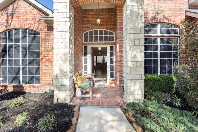 property entrance featuring covered porch, brick siding, and stone siding