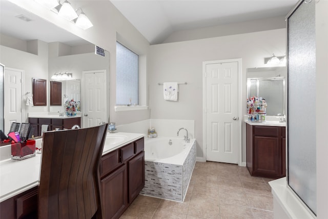 bathroom with a garden tub, two vanities, vaulted ceiling, tile patterned floors, and a stall shower