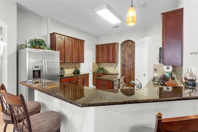 8707 Rolling Rapids Rd, Humble, TX 77346 - kitchen with backsplash, a peninsula, a breakfast bar, decorative light fixtures, and dark stone counters