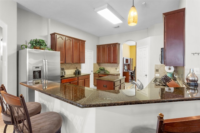 kitchen with a peninsula, tasteful backsplash, arched walkways, and a breakfast bar