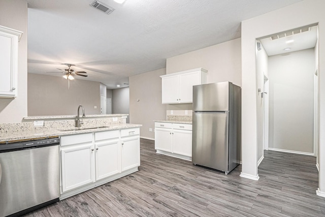 24134 Griffin House Ln, Katy, TX 77493 - kitchen with appliances with stainless steel finishes, ceiling fan, light wood-style floors, white cabinetry, and a peninsula