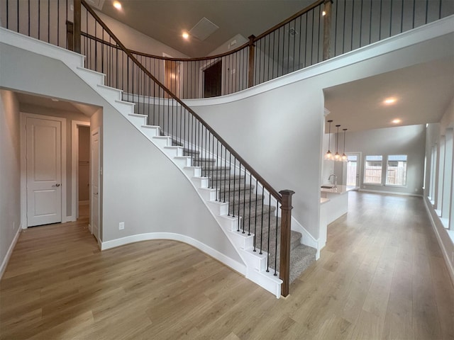 staircase featuring a high ceiling, baseboards, and wood finished floors