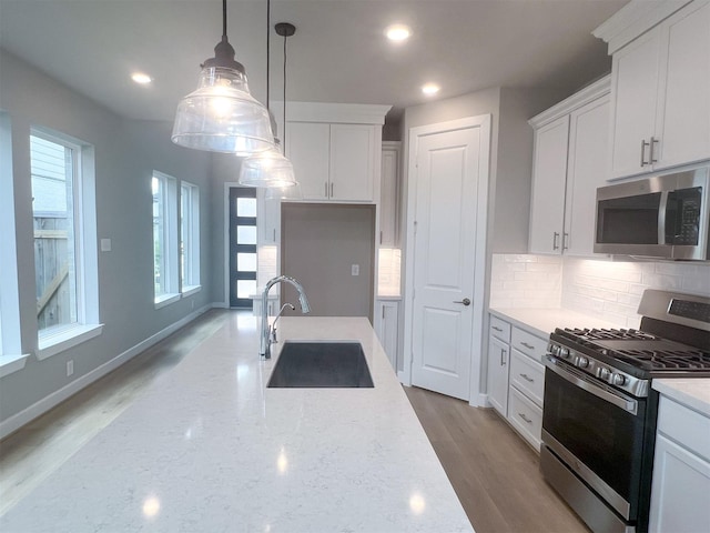 kitchen featuring tasteful backsplash, white cabinetry, stainless steel appliances, and a sink