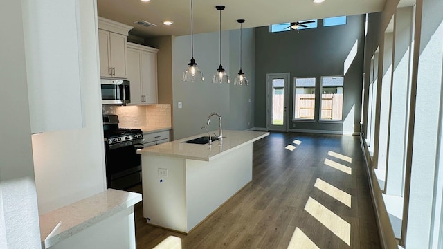 kitchen with stainless steel microwave, visible vents, open floor plan, black range with gas cooktop, and a sink