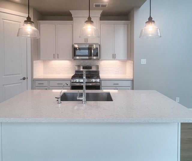 kitchen featuring appliances with stainless steel finishes, light stone countertops, visible vents, and tasteful backsplash