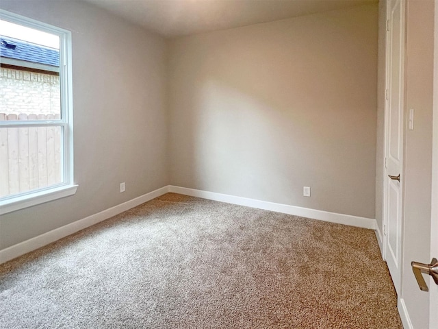 empty room featuring carpet and baseboards