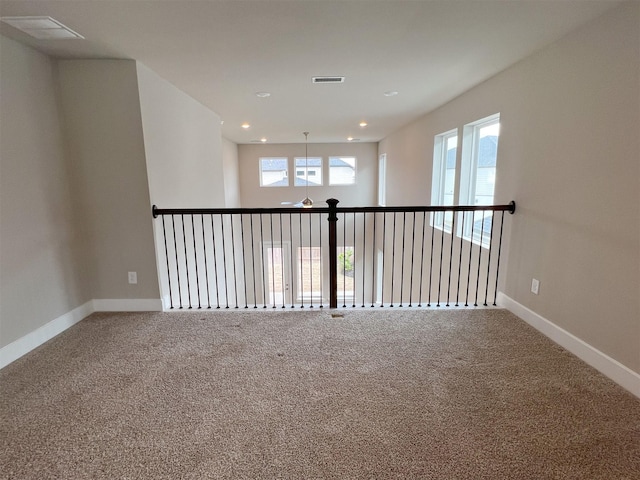 empty room featuring carpet, visible vents, and baseboards