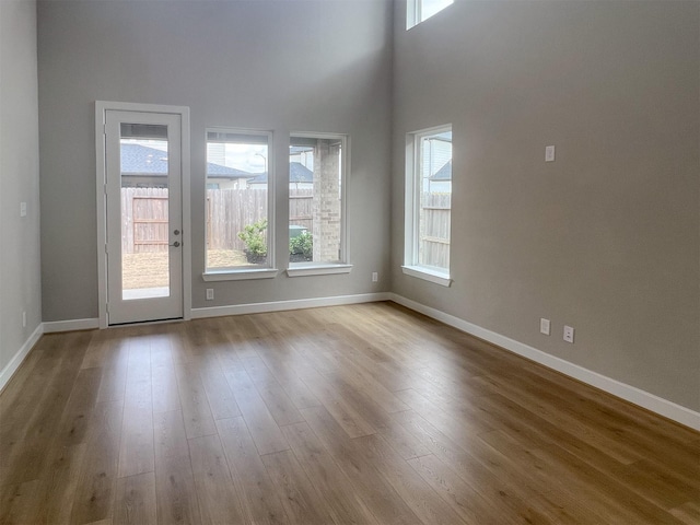 empty room with a high ceiling, wood finished floors, and baseboards