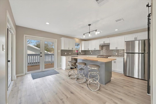 kitchen with visible vents, decorative backsplash, a kitchen island, freestanding refrigerator, and french doors