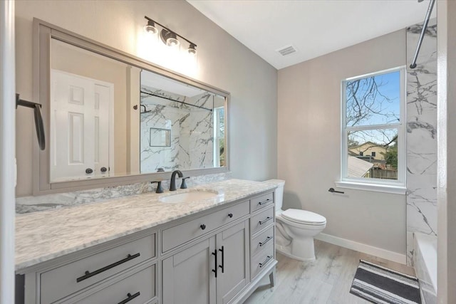 full bath with toilet, vanity, visible vents, baseboards, and a marble finish shower