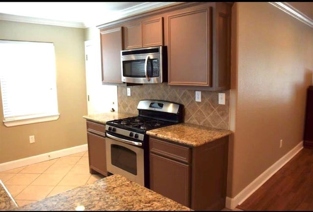 kitchen featuring ornamental molding, stainless steel appliances, tasteful backsplash, and baseboards