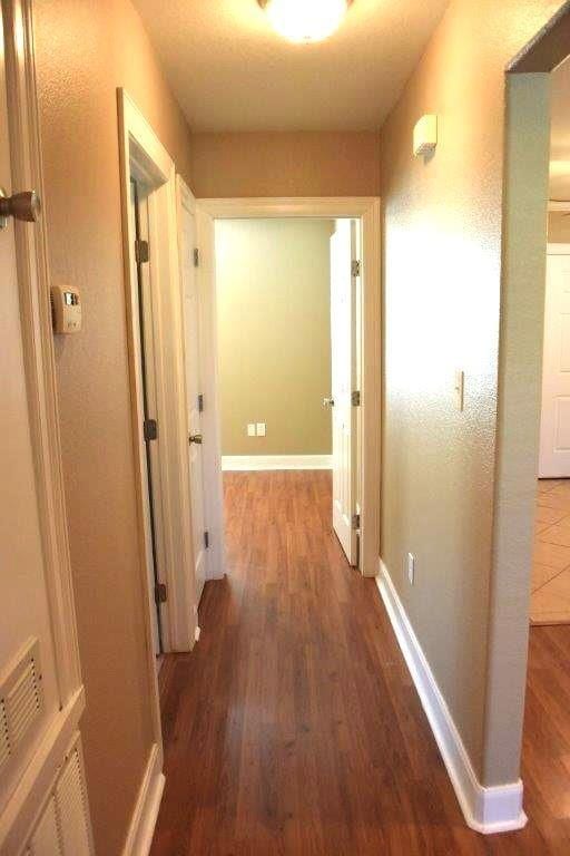 hallway featuring visible vents, baseboards, and wood finished floors