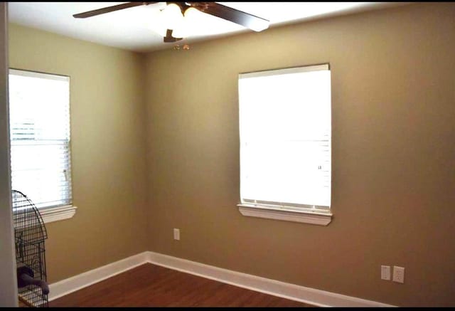 unfurnished room featuring dark wood-style flooring, ceiling fan, and baseboards