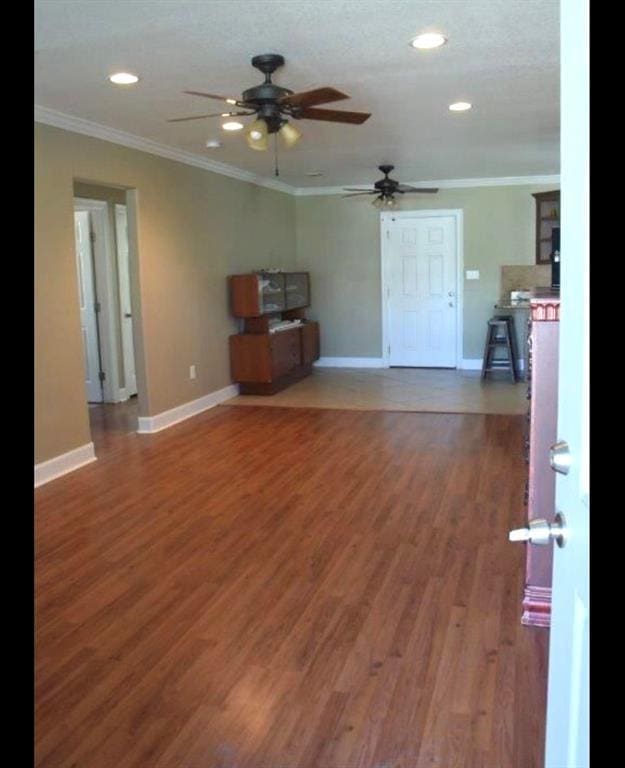 unfurnished living room with crown molding, baseboards, and wood finished floors