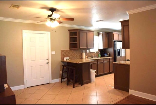 kitchen with tasteful backsplash, stainless steel fridge, visible vents, and crown molding