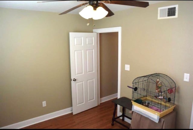 interior space with a ceiling fan, visible vents, baseboards, and wood finished floors