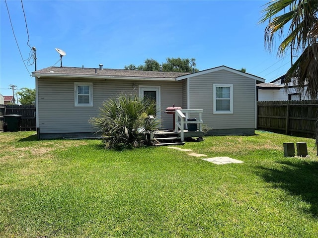 rear view of house with a deck, a yard, and fence