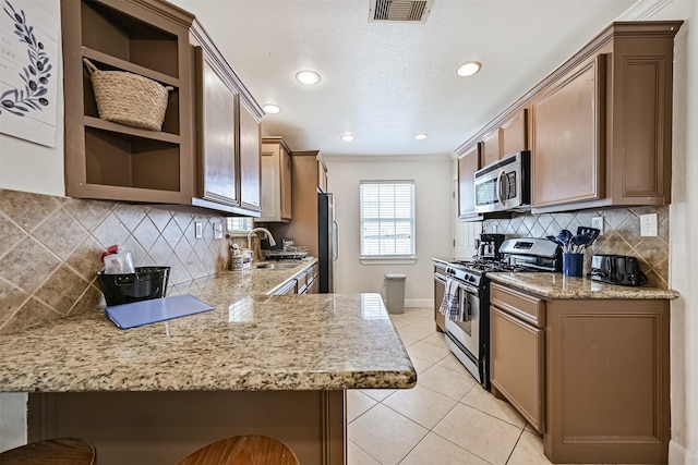 2009 Neumann Dr, Galveston, TX 77551 - kitchen with stainless steel appliances, open shelves, a sink, light tile patterned flooring, and baseboards