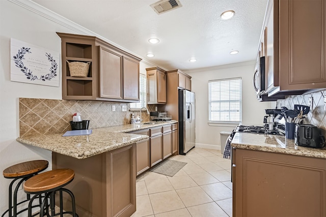 2009 Neumann Dr, Galveston, TX 77551 - kitchen featuring appliances with stainless steel finishes, ornamental molding, a breakfast bar area, baseboards, and backsplash