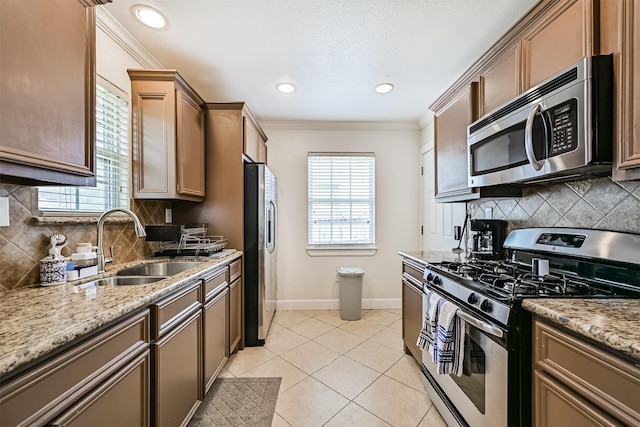 2009 Neumann Dr, Galveston, TX 77551 - kitchen featuring stainless steel appliances, a sink, baseboards, healthy amount of natural light, and crown molding