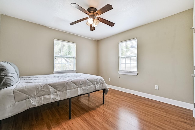 2009 Neumann Dr, Galveston, TX 77551 - bedroom with multiple windows, light wood-style flooring, baseboards, and ceiling fan