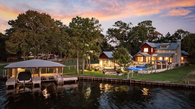 view of dock featuring an outdoor pool, a water view, a yard, and boat lift