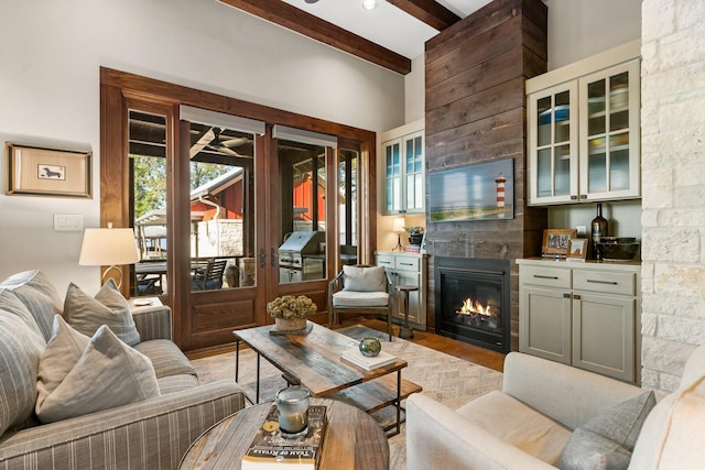 living room featuring light wood-style floors, beam ceiling, and a fireplace