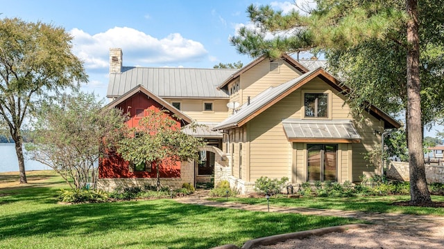 view of front facade featuring a standing seam roof, metal roof, a chimney, and a front lawn