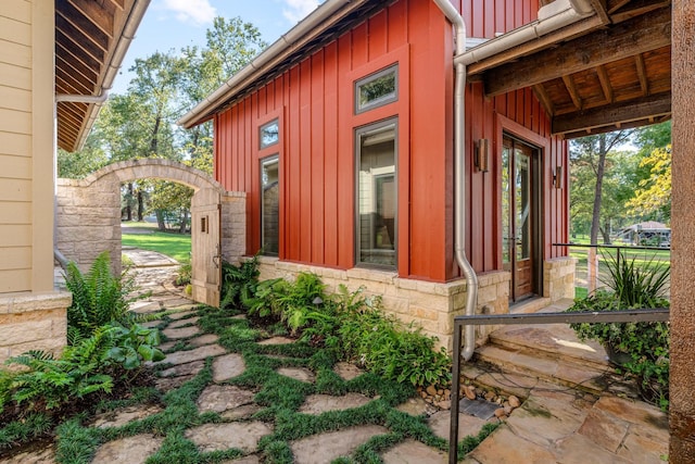 view of property exterior featuring stone siding, board and batten siding, and a gate