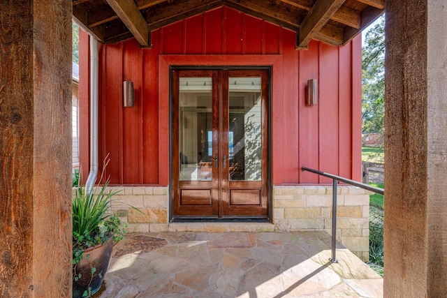 doorway to property with stone siding, french doors, and board and batten siding