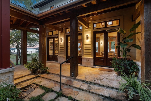 property entrance with stone siding, french doors, and covered porch