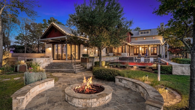 back of house with french doors, a patio area, metal roof, and a fire pit