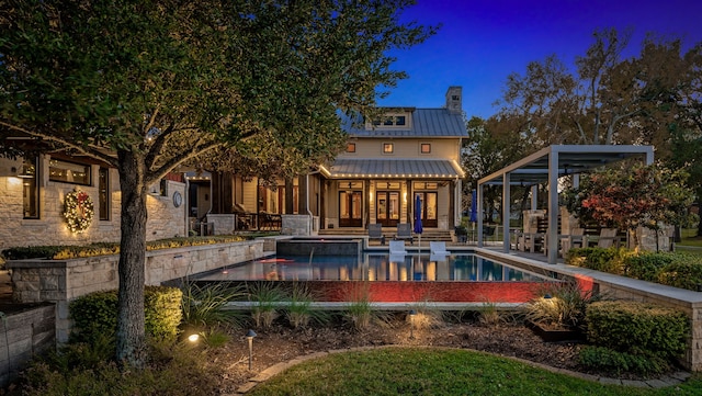 rear view of property with metal roof, a chimney, an outdoor pool, a standing seam roof, and a patio area