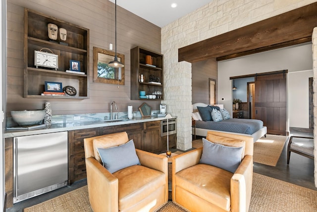 bar featuring a barn door, concrete floors, a sink, beamed ceiling, and stainless steel built in refrigerator