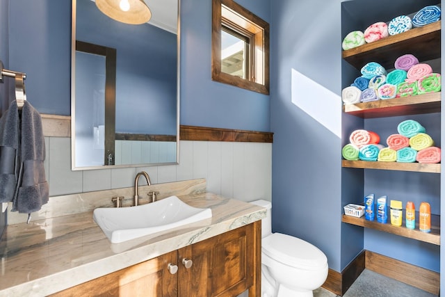 bathroom featuring toilet, wainscoting, and vanity