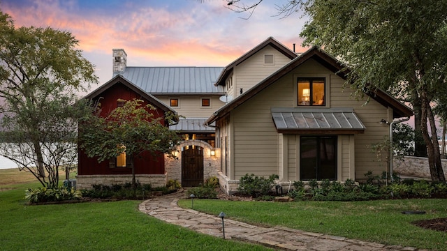 back of property featuring metal roof, a yard, a standing seam roof, and a chimney