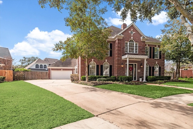 georgian-style home with concrete driveway, brick siding, a front lawn, and a chimney