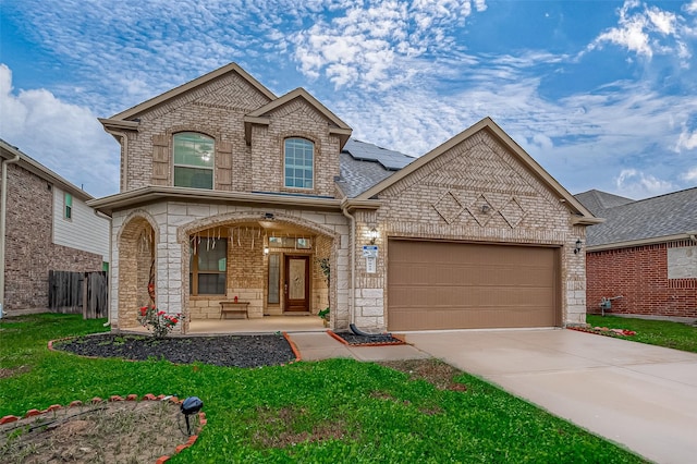 view of front facade featuring a garage, driveway, covered porch, roof mounted solar panels, and brick siding