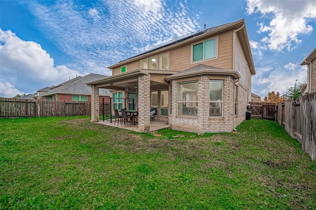 back of property with a patio area, brick siding, a lawn, and a fenced backyard