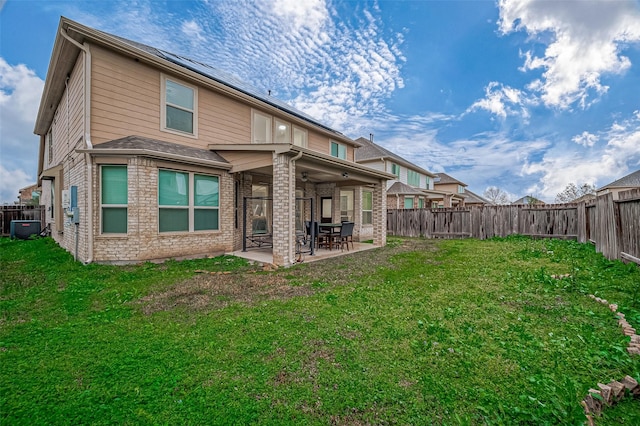 back of property with a fenced backyard, a lawn, central AC, and a patio