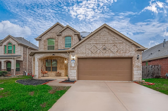 view of front of house with driveway, brick siding, an attached garage, and fence