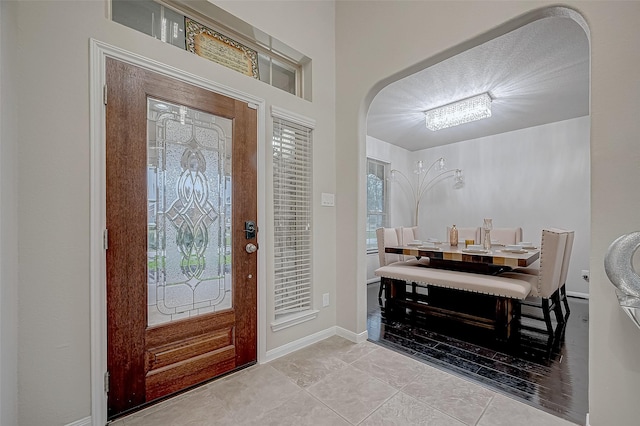 foyer with arched walkways, tile patterned flooring, and baseboards