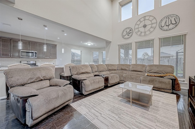 living room with a high ceiling, dark wood-style flooring, and visible vents