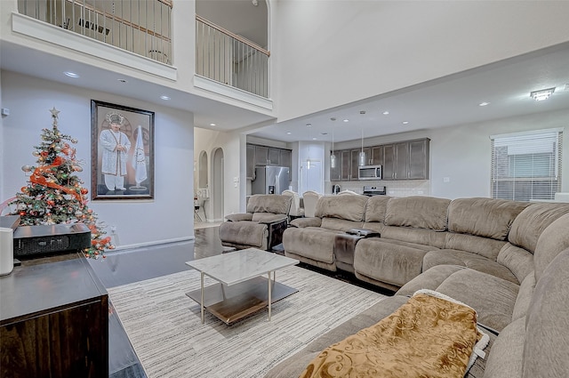 living room with arched walkways, a high ceiling, and recessed lighting