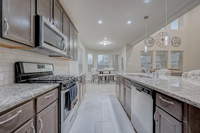 kitchen with dark brown cabinetry, decorative backsplash, stainless steel appliances, and a sink