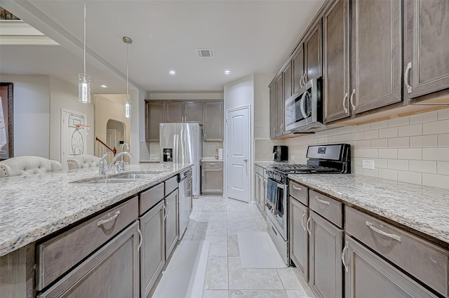 kitchen with appliances with stainless steel finishes, visible vents, backsplash, and light stone countertops