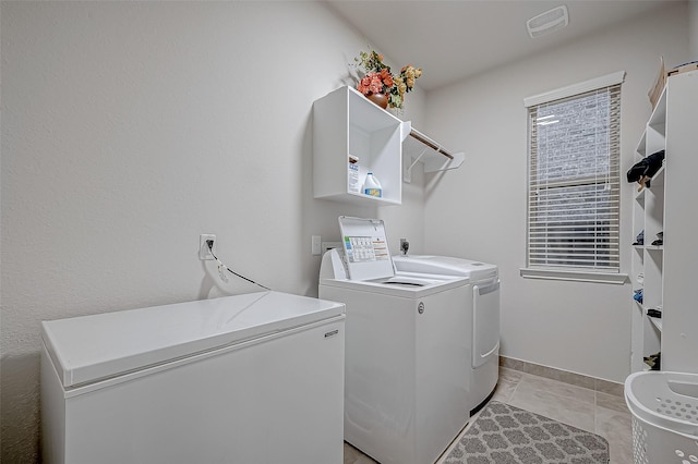 clothes washing area with laundry area, washing machine and dryer, visible vents, and baseboards