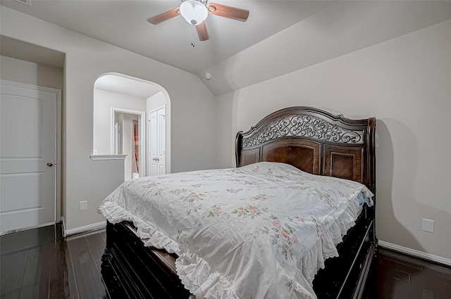 bedroom featuring vaulted ceiling, arched walkways, dark wood finished floors, and baseboards